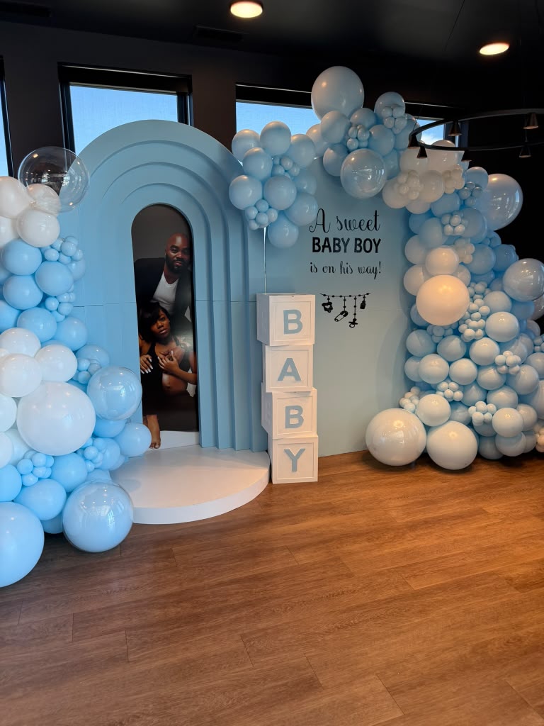 Blue and white balloon installation with a baby shower welcome backdrop