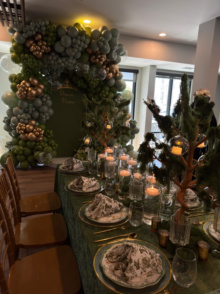 Dark green tablescape with patterned place settings, candles and balloon installation