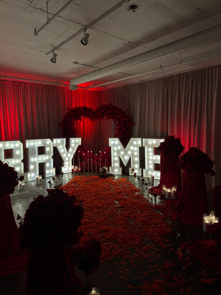 Red floral proposal installation with illuminated marquee letters